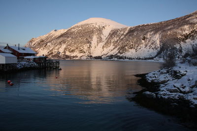 Scenic view of lake by snowcapped mountains against clear sky