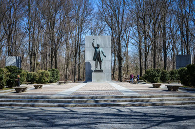 Statue of bare trees in city against sky