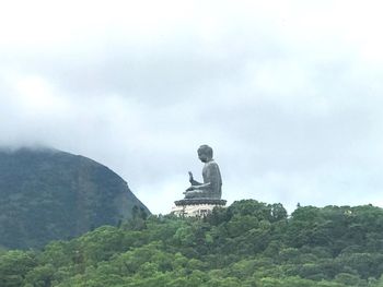 Statue against trees and mountains against sky