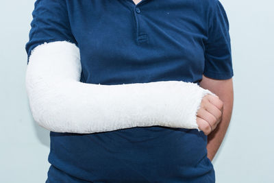 Midsection of woman with broken hand standing against wall