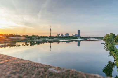 View of river against buildings during sunset