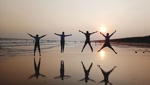 Silhouette people on beach against sky during sunset