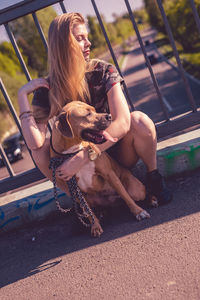 Young woman embracing dog while sitting on footbridge