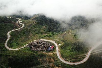 High angle view of winding road amidst landscape during foggy weather