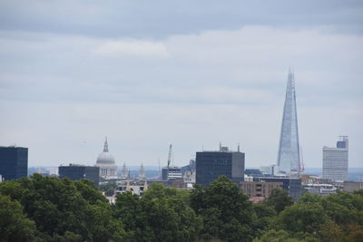 Buildings in city against cloudy sky