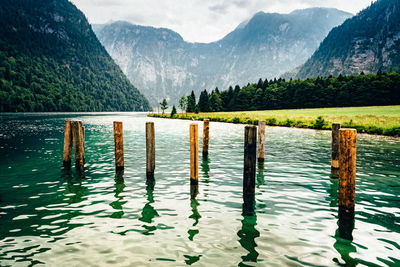 Wooden posts in lake against mountains