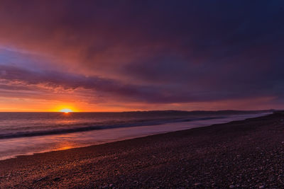 Scenic view of sea against dramatic sky during sunset