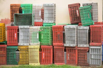 Stack of crates arranged on field against wall