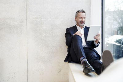 Smiling businesssman using tablet at the window