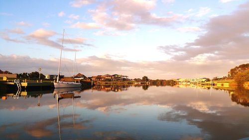 Sailboats moored in lake against sky during sunset