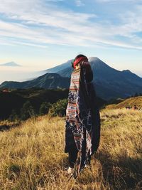 Woman wearing shawl while standing on mountain against sky