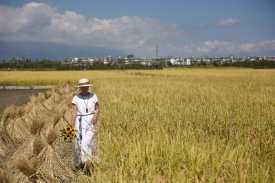 Rear view of man standing on field against sky