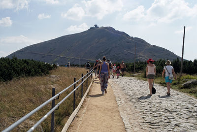 People walking on mountain against sky