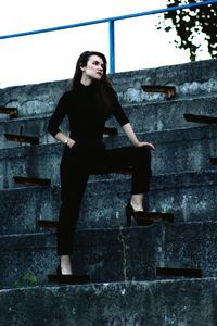 Portrait of young woman sitting on floor in city