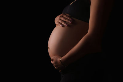 Side view of woman touching hair over black background