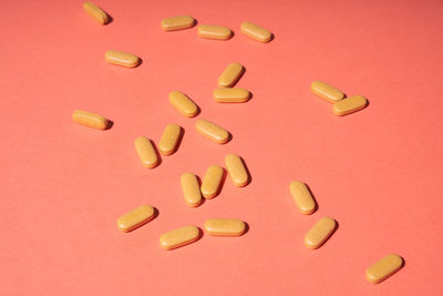 Few orange pills randomly on a pink background