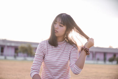 Beautiful young woman standing against sky