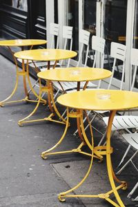 Empty chairs and tables at sidewalk cafe