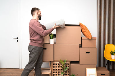 Mature man unpacking things from boxes while moving in new apartment.