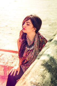 Young woman sitting on retaining wall