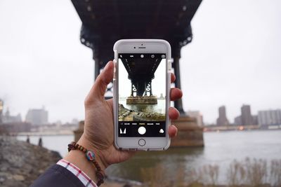 Cropped image of man photographing through smart phone