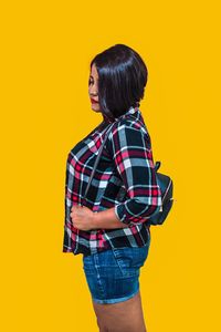 Full length of woman standing against yellow background