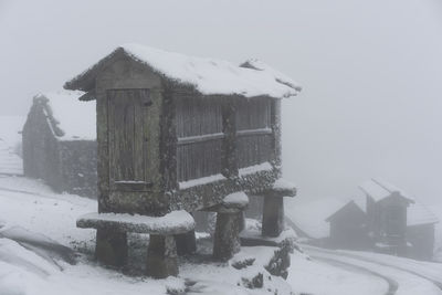 Snow covered houses by buildings against sky