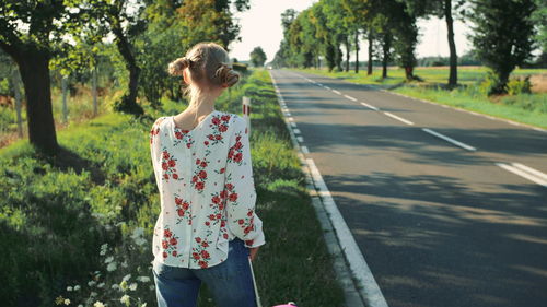 Woman with suitcase hitchhiking on roadside