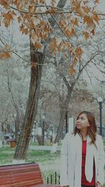 Young woman standing in autumn leaves