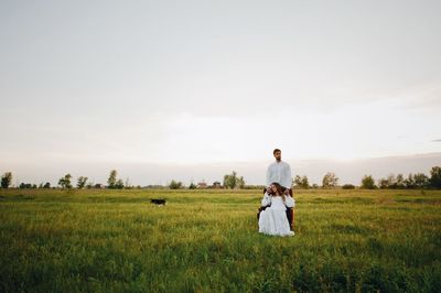 Bride and groom on field against sky