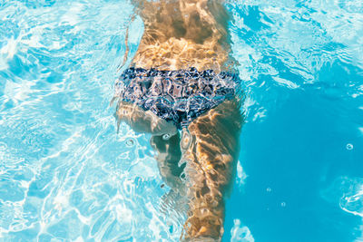 Low section of person swimming in pool