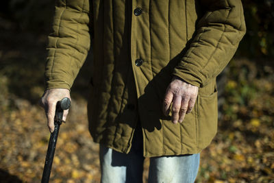 Old man with pole for support when walking. old hands. man in poor clothes. retired in russia.