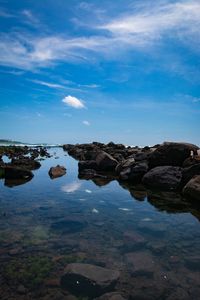 Rocks in water against blue sky