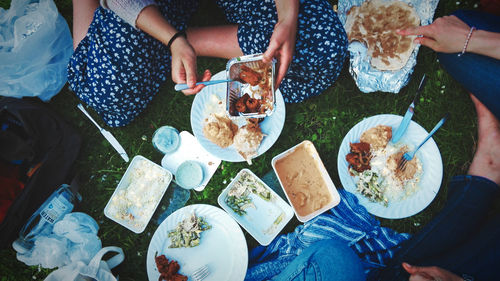 Low section of people eating food on grassy field