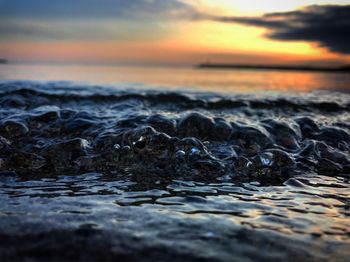 Surface level of sea against sky during sunset