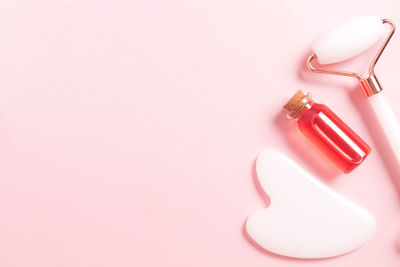 High angle view of pills spilling from bottle against pink background