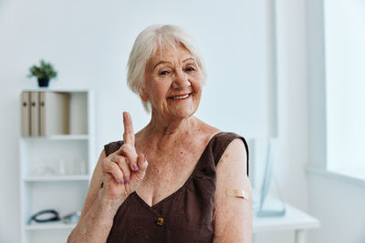 Smiling senior woman gesturing at clinic
