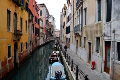 Rear view of people on canal amidst buildings in city