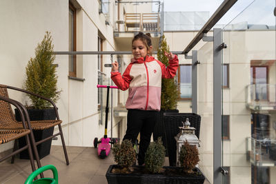 Portrait of young woman standing against building