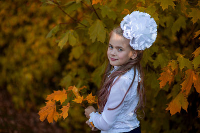 Portrait of cute girl standing by plants during autumn