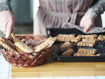  the hands of an elderly woman remove the prepared freshly baked cookies from the baking sheet .