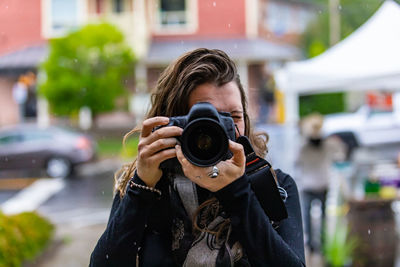 Portrait of woman photographing on city street