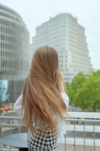 Rear view of young woman standing outdoors against sky