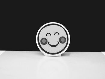 Close-up of smiley face on table against black background
