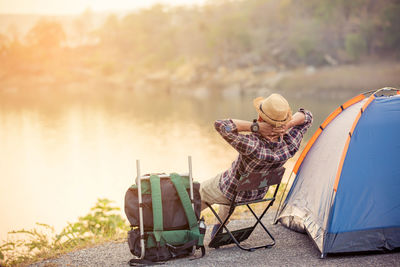 People sitting on tent by lake