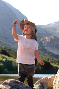 Full length of boy standing on rock against sky