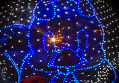 Close-up of hand holding illuminated lights at night