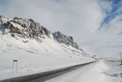 Road by snowcapped mountains against sky