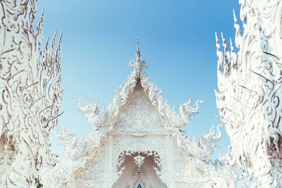 Beautiful bright white oriental palace with clear pond statues and ornamental bridge with blue sky on background in thailand