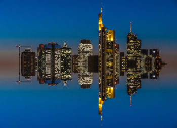 Low angle view of illuminated cityscape against clear blue sky